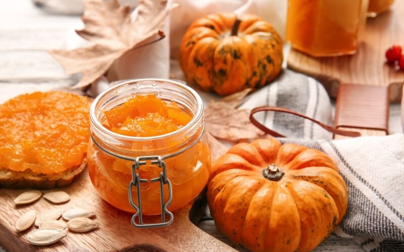 Small pumpkins and a jar of pumpkin jam on a table