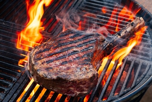 a delmonico steak on a grill with flames all aroundn it