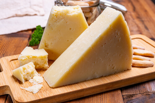 a wedge of pecorino romano cheese sits on a cutting board