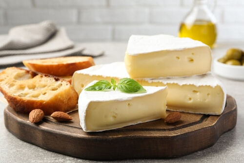 wedges of brie cheese sit on a cutting board next to some crackers