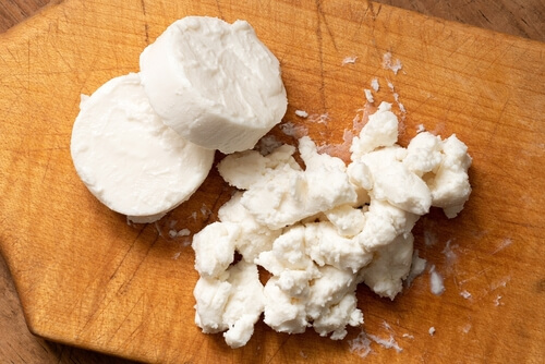 sliced and crumbled goat cheese on a cutting board