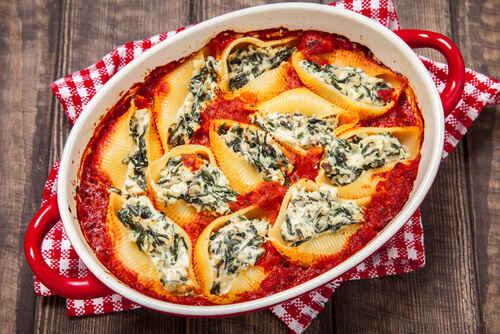 a dish of spinach stuffed shells in red sauce