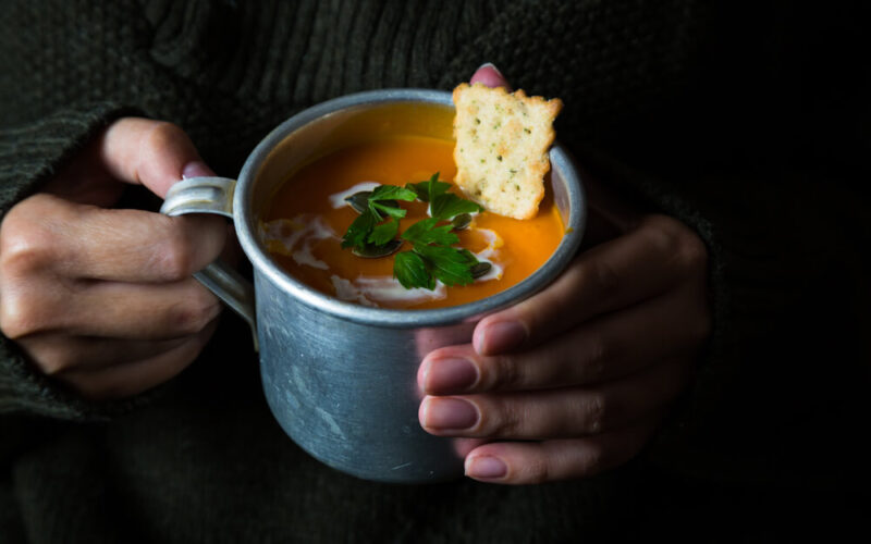 A bowl of tomato soup with a cracker floating on top